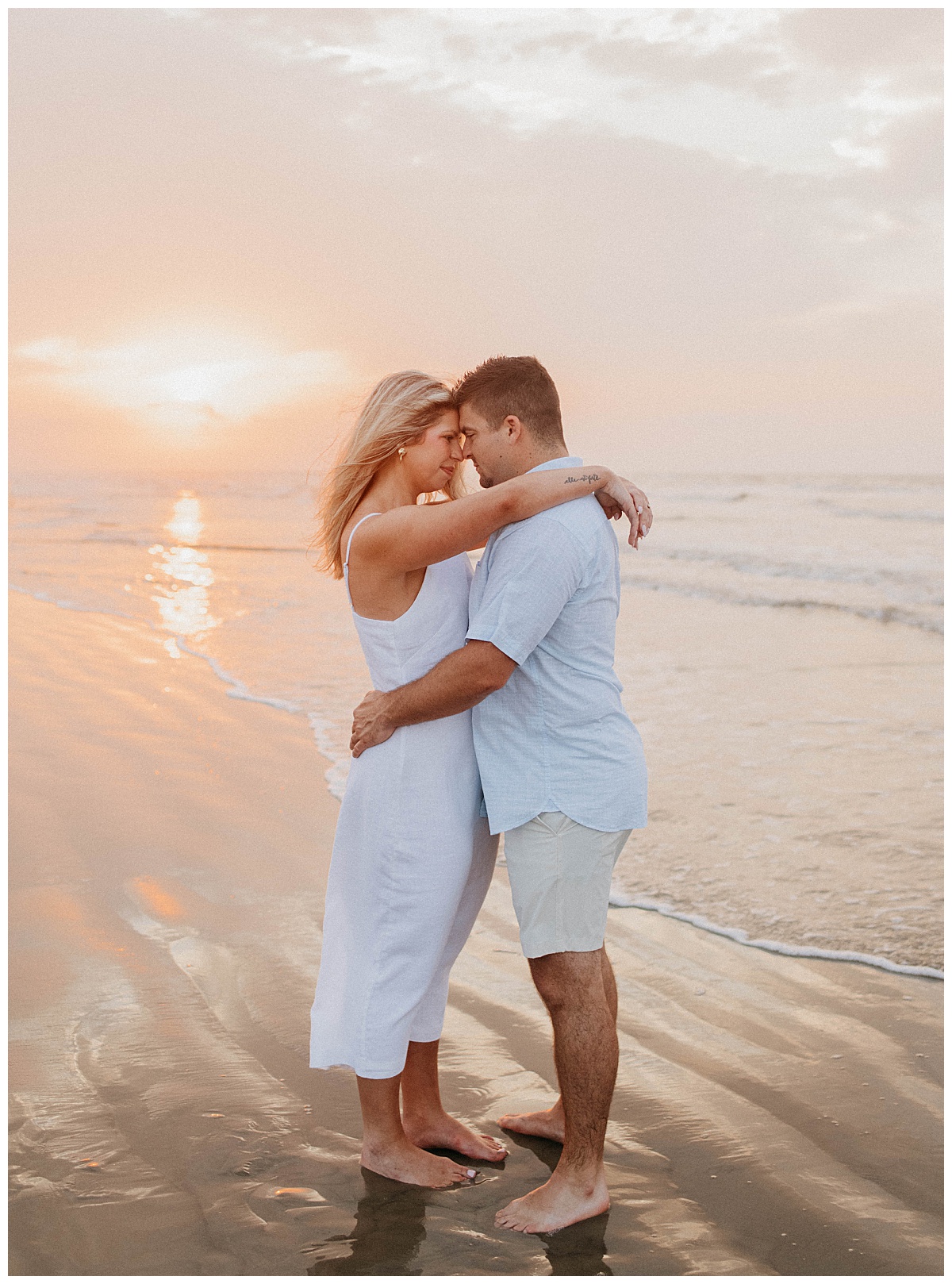 woman has arms around man's shoulders at beach during Galveston sunrise engagement session