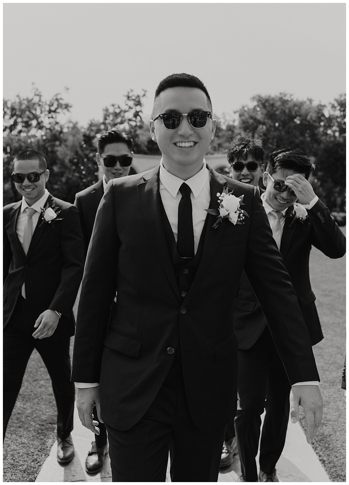 groom wears sunglasses and walks with his groomsmen at Knotting Hill Place