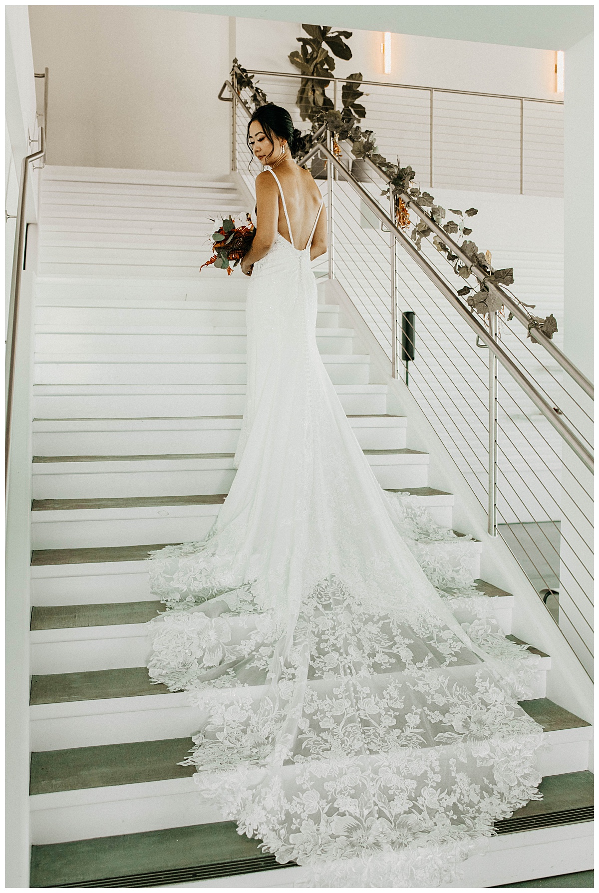 bride stands on stairs with train trailing behind her by Stephanie J Zamora Photography