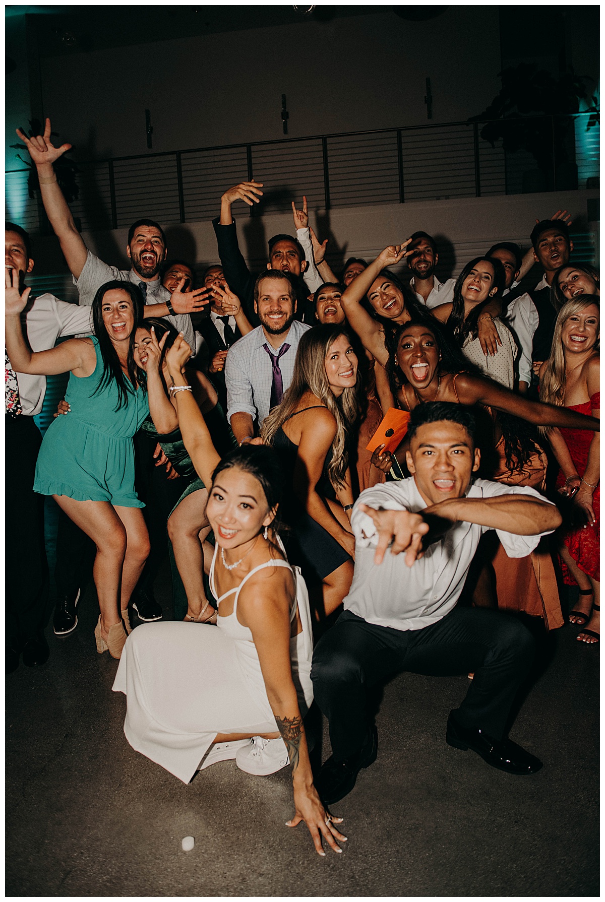 guests stand together laughing and smiling on the dance floor by Stephanie J Zamora Photography